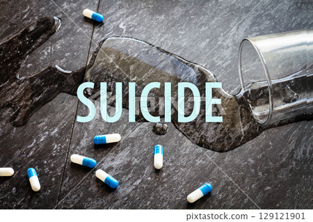 The inscription suicide on the background of scattered pills and spilled water. 129121901