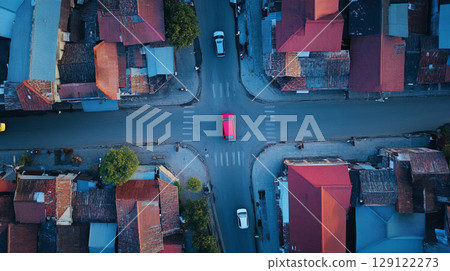 Top view of a car moving through urban streets with buildings and intersections visible below 129122273