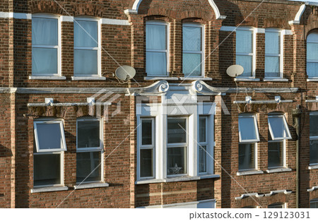 Facade of an residential building in red bricks with classic glass windows in london. 129123031
