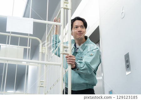 A young male worker carrying luggage in a warehouse 129123185