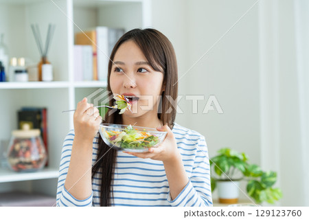 A young woman eating a salad A young woman eating a salad 129123760