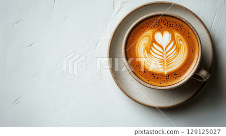 Cup of cappuccino with heart-shaped latte art on saucer, isolated on textured white background, minimal coffee concept. 129125027