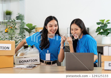 Volunteer excitement. Women celebrating success in donation efforts at community center. 129125133