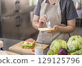Woman spreading mayonnaise on bread for a sandwich. 129125796