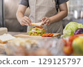 Hands placing final slice of bread on a sandwich. 129125797