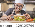 Asian Female Chef Assembling Fresh Sandwich in Kitchen 129125799