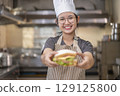 Smiling Asian Female Chef Holding Sandwich in Kitchen 129125800