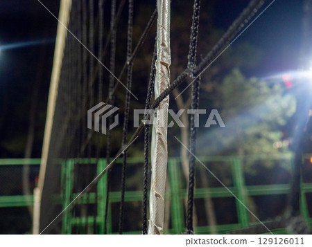 Beach volleyball court in the evening. Available infrastructure. Empty sports ground. Volleyball game concept. Sports mesh. Entertainment in the park.   Under the lanterns 129126011