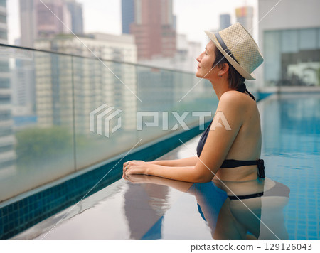 Young woman relaxing by the pool at a Kuala Lumpur hotel Young woman relaxing by the pool at a Kuala Lumpur hotel 129126043
