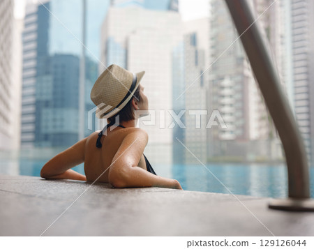 Young woman relaxing by the pool at a Kuala Lumpur hotel Young woman relaxing by the pool at a Kuala Lumpur hotel 129126044