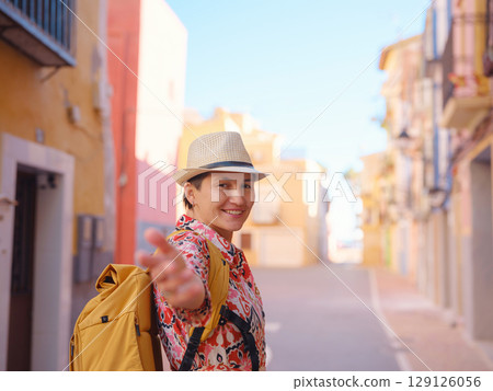 Woman strolls through colorful streets of Spanish coastal town 129126056