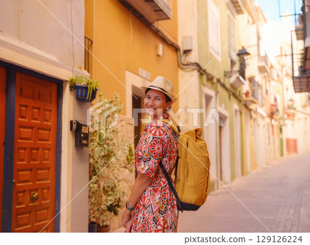 Woman strolls through colorful streets of Spanish coastal town 129126224