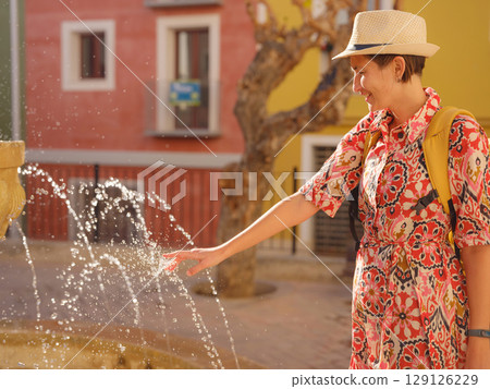 Woman strolls through colorful streets of Spanish coastal town 129126229