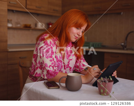 young woman working on tablet at kitchen young woman working on tablet at kitchen 129126386