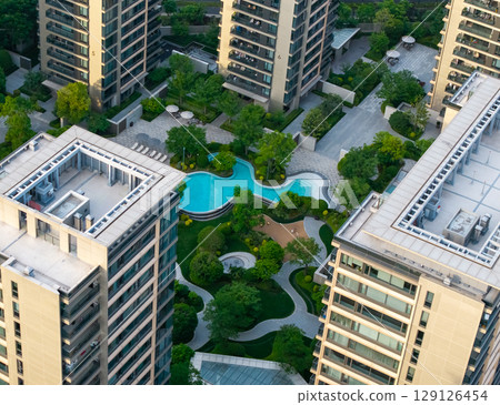 Aerial view of modern residential area featuring greenery, water features, and recreational spaces in urban setting. Aerial view of modern residential area featuring greenery, water features, and recreational spaces in urban setting. 129126454