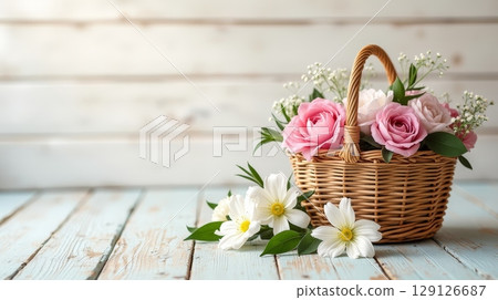 Wicker basket with pink roses and white flowers on rustic wooden table. Floral arrangement with copy space. Spring and romantic concept 129126687
