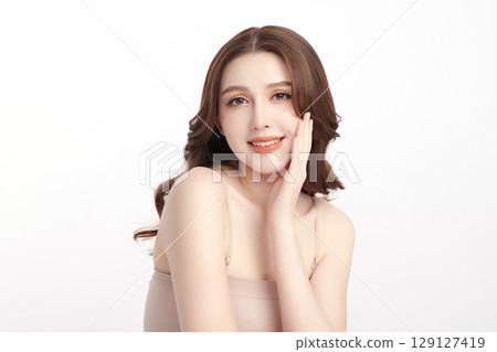 A beautiful young Asian woman with clean, fresh skin against a white background. Skincare, facial treatment, cosmetology, beauty, and spa. An elegant portrait of an Asian woman. 129127419