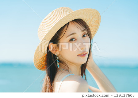 戴著草帽的女人，背景是海和藍天 129127603