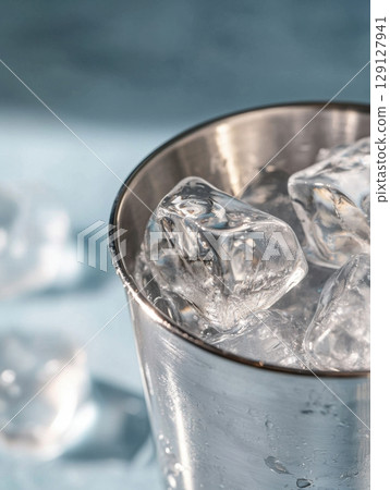 Shiny stainless steel cup filled with fresh ice cubes in minimalist composition Shiny stainless steel cup filled with fresh ice cubes in minimalist composition 129127941