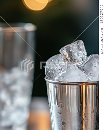 Transparent ice cubes stacked in a metallic container with condensation details Transparent ice cubes stacked in a metallic container with condensation details 129127942