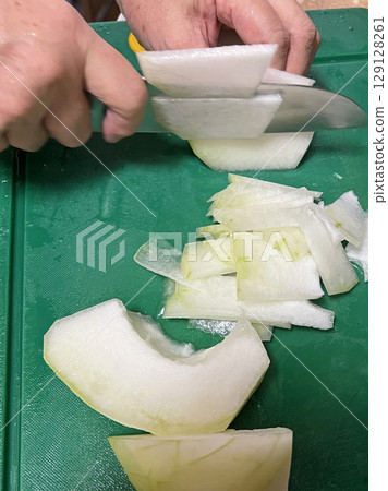 Filming the mother slicing winter melon with a kitchen knife to prepare soup 129128261