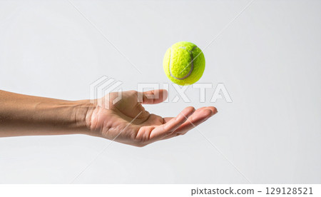 hand with tennis ball, a tennis player's hand tossing a tennis ball mid air, with a white wristband on a clean background. Captures the moment of focus and precision before the serve begins 129128521
