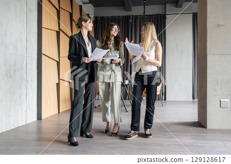 Businesswomen having a casual conversation in a modern office lobby 129128617