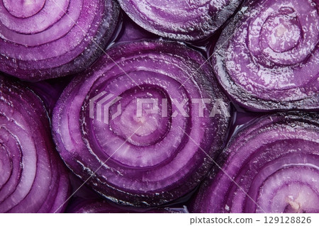 A close-up of fresh red onion slices arranged in a seamless pattern. The purple tones and detailed texture make it ideal for backgrounds, food packaging, food blogs or healthy eating campaigns. Banner 129128826