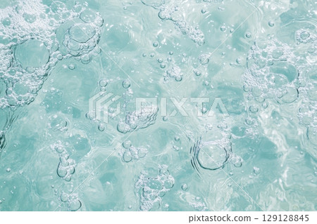 Close-up of abstract turquoise bubbles in liquid. Soft glow, smooth shapes, delicate texture. Macro shot with vibrant light. Fresh, pure, clean concept. Background, chemistry, skincare. Banner 129128845