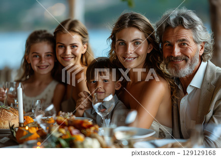 A family gathering around the table for a multi-generational dinner. Generations come together, bonding over a delicious meal. 129129168