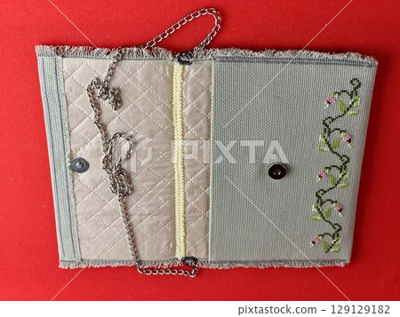 Handmade retro clutch bag on a red background. Vintage bag on a chain handle. Inside the bag is trimmed with silk fabric and embroidered with beads. 129129182