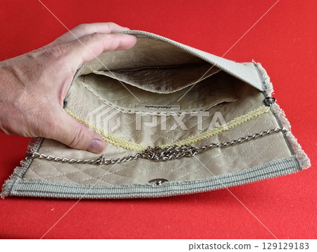 Handmade retro clutch bag on a red background. Vintage bag on chain handle. Inside the bag is trimmed with silk fabric and embroidered with beads. 129129183