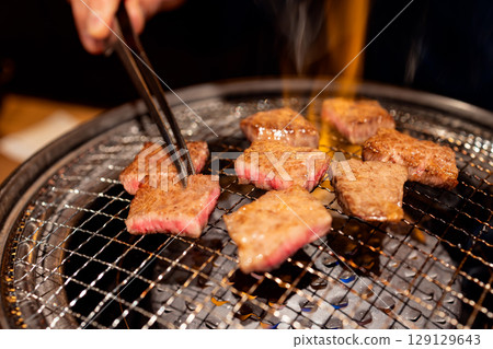 Grilling premium A5 Wagyu beef slices on traditional metal grate over open flame Grilling premium A5 Wagyu beef slices on traditional metal grate over open flame 129129643