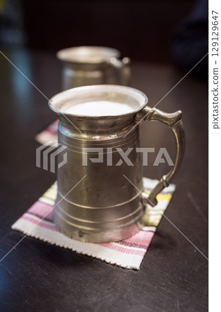 Vintage Japanese metal beer mugs filled with beer, photographed on a dark wooden table Vintage Japanese metal beer mugs filled with beer, photographed on a dark wooden table 129129647
