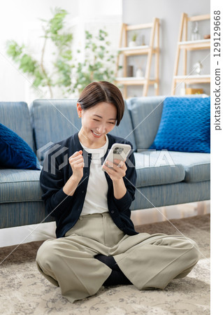 A woman looking at her smartphone in the living room 129129668