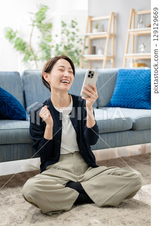 A woman looking at her smartphone in the living room 129129669