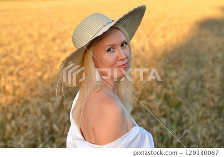 Young woman enjoying a carefree moment in a wheat field near a forest during sunset Young woman enjoying a carefree moment in a wheat field near a forest during sunset 129130067