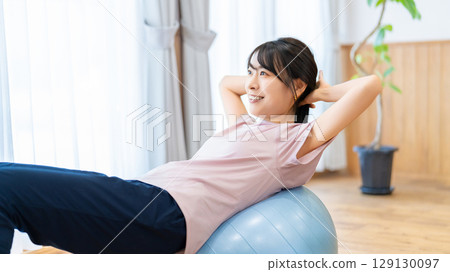Woman exercising with a balance ball Woman exercising with a balance ball 129130097