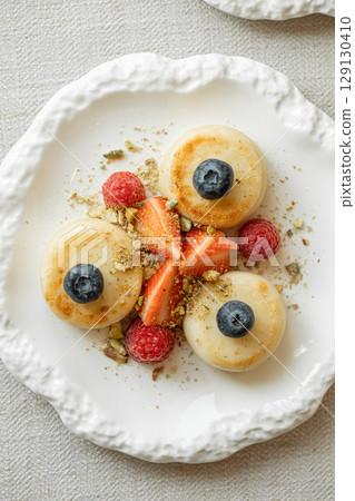 Syrniki pancakes with berries and pistachios 129130410
