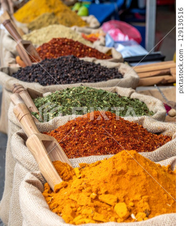 Colorful Spices in Burlap Sacks with Wooden Scoops at Open Market Display 129130516
