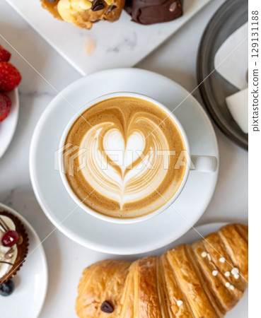 Latte Art Heart Design Surrounded by Pastries and Fruits on Marble Tabletop 129131188