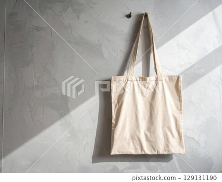 Beige Cotton Tote Bag Hanging on Concrete Wall in Natural Light 129131190