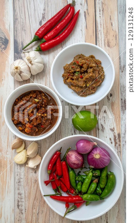Overhead Shot of Red and Green Chilies with Onions and Garlic on Wood 129131248