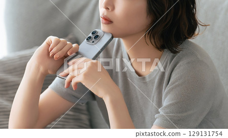 A woman thinking with a smartphone 129131754