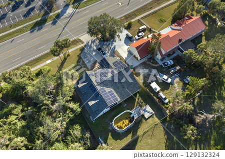Aerial view of regular american home roof with blue solar photovoltaic panels for producing clean ecological electric energy. Renewable electricity with zero emission concept 129132324