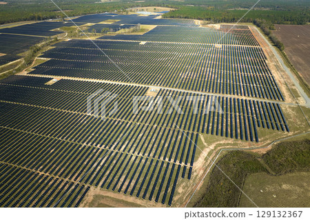 Aerial view of large sustainable electrical power plant with rows of solar photovoltaic panels for producing clean electric energy. Concept of renewable electricity with zero emission Aerial view of large sustainable electrical power plant with rows of solar photovoltaic panels for producing clean electric energy. Concept of renewable electricity with zero emission 129132367
