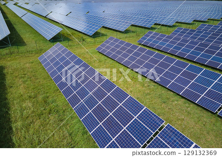 Aerial view of large sustainable electrical power plant with rows of solar photovoltaic panels for producing clean electric energy. Concept of renewable electricity with zero emission Aerial view of large sustainable electrical power plant with rows of solar photovoltaic panels for producing clean electric energy. Concept of renewable electricity with zero emission 129132369