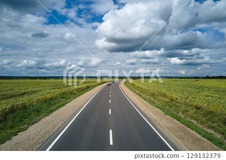 Aerial view of intercity road between green agricultural fields with fast driving cars. Top view from drone of highway traffic Aerial view of intercity road between green agricultural fields with fast driving cars. Top view from drone of highway traffic 129132379