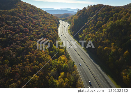 Aerial view of I-40 freeway in North Carolina leading to Asheville through Appalachian mountains in golden fall with fast moving trucks and cars. Interstate transportation concept Aerial view of I-40 freeway in North Carolina leading to Asheville through Appalachian mountains in golden fall with fast moving trucks and cars. Interstate transportation concept 129132380
