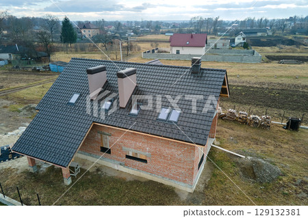 Aerial view of house roof top covered with ceramic shingles. Tiled covering of building under construction Aerial view of house roof top covered with ceramic shingles. Tiled covering of building under construction 129132381